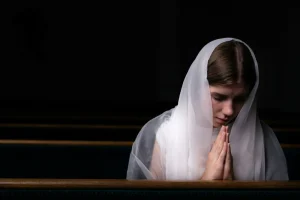 Woman wearing veil praying in Church (Photo by Volodymyr Hryshchenko on Unsplash)